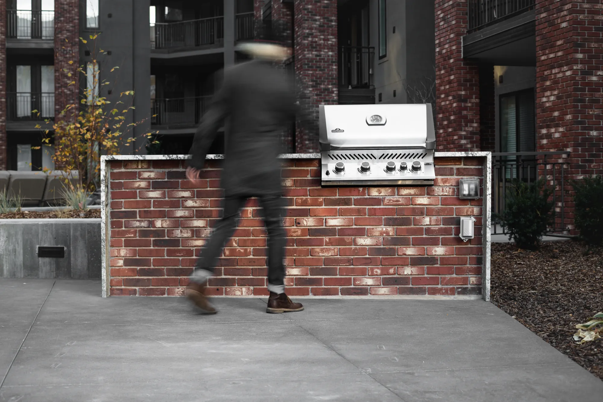 A figure walking past the south courtyard grill station, blurred in motion
