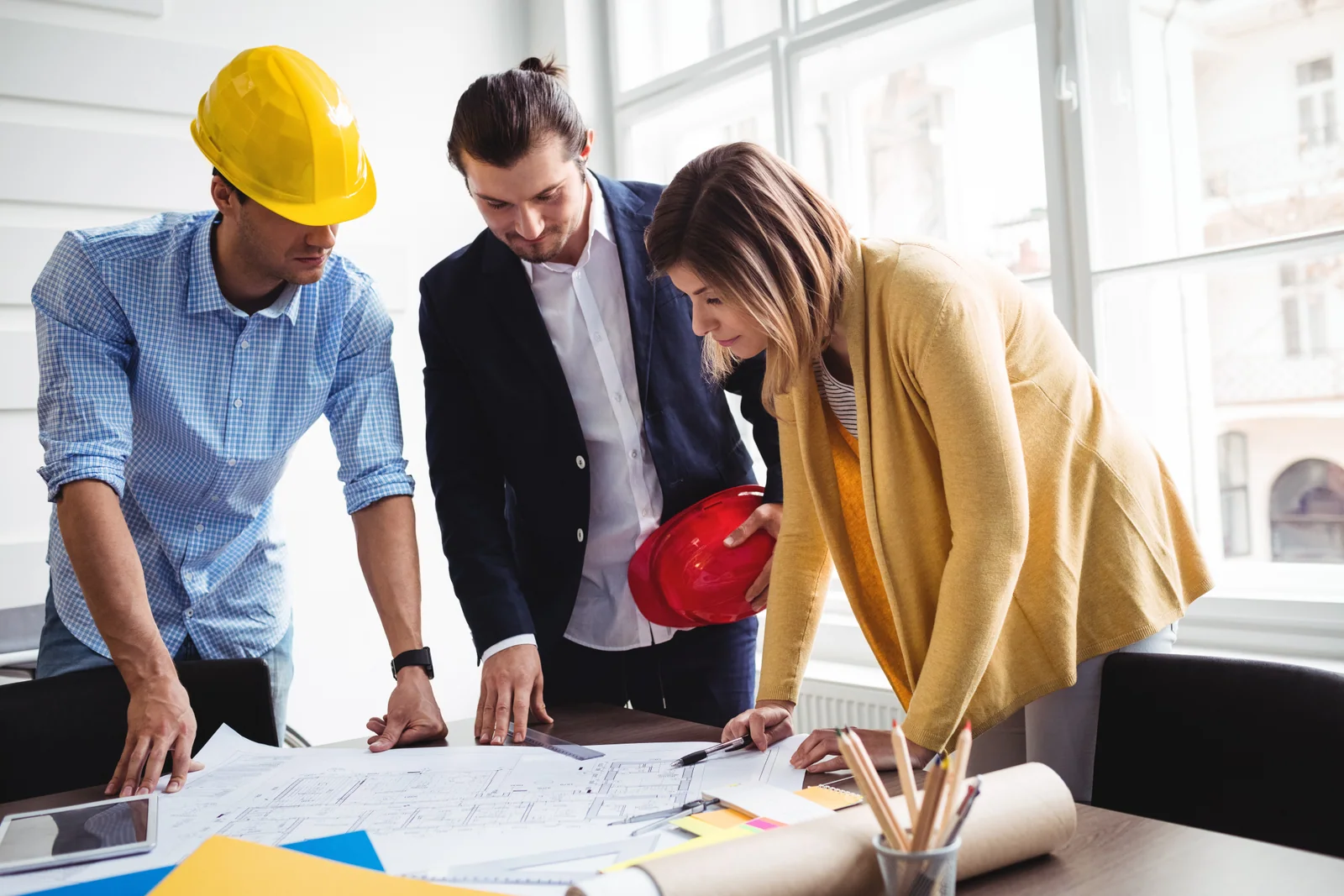 Two men and a woman reviewing construction plans at a construction site