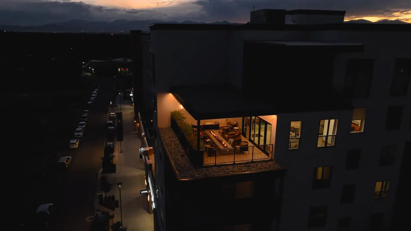 The Grandeur at dusk from above, the lit clubroom projecting over the street with the Wasatch behind