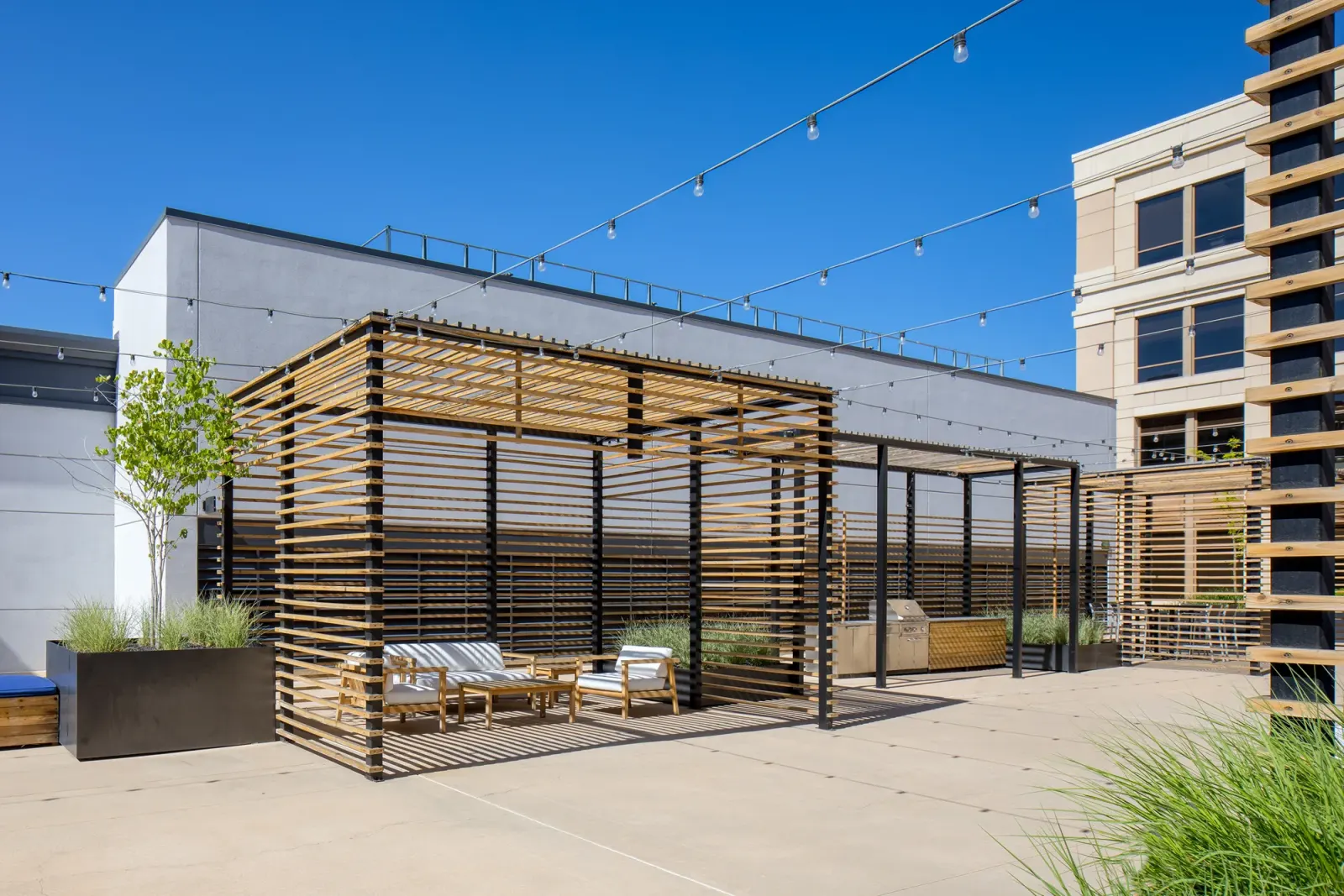 Hidden Gem rooftop: the slatted cedar pavilion and lounge under string lights against a blue sky