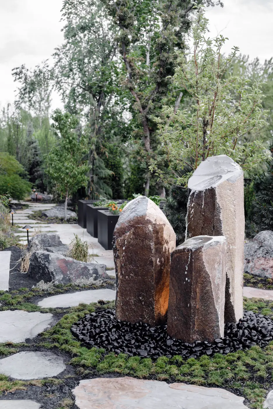 Basalt column fountains rising from a bed of black stone and grasses