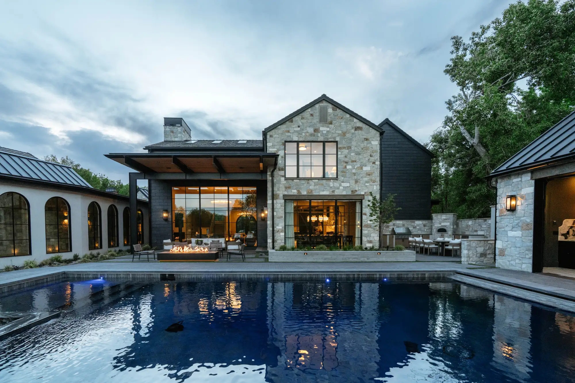 The pool at dusk, the lit house and covered patio reflected in still water