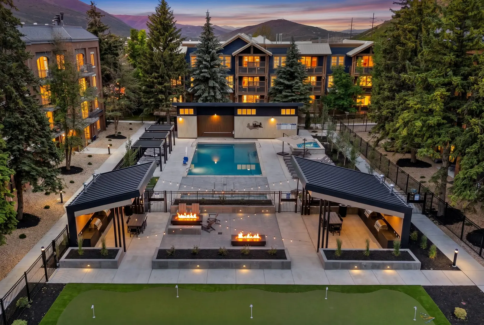 Park Station Condos amenity courtyard from above at dusk, the putting green, fire lounge and pool between the condo buildings