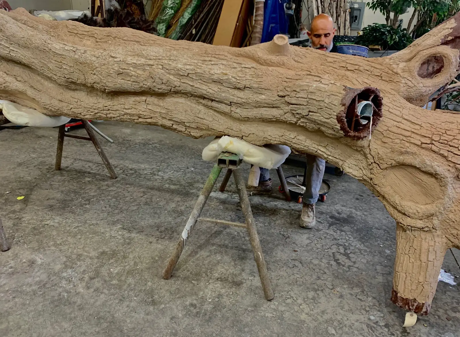 The steel trunk of the art tree on sawhorses in the fabricator’s shop