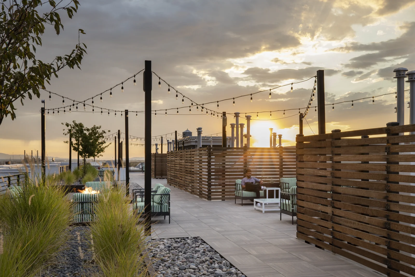 Skyhouse rooftop lounge at sunset, wood-slat screens separating shared and private rooms
