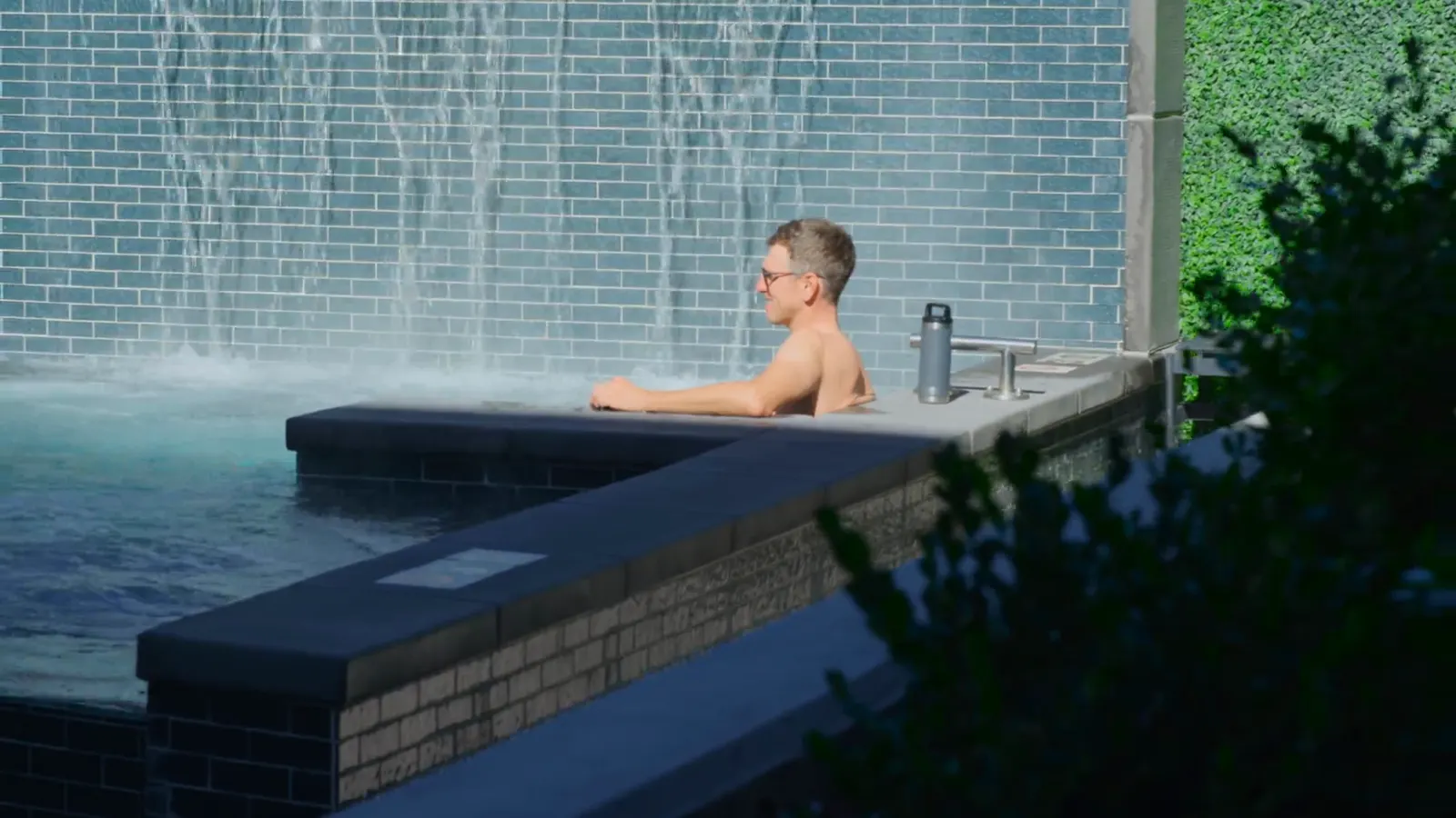 A person in the spa beside the Slate courtyard water wall